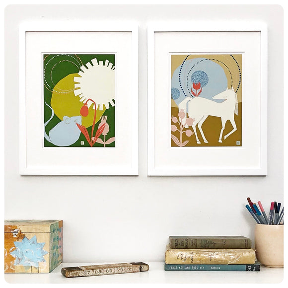 Two prints on a wall, one with a blue mouse smelling an orange flower, the other a white filly turning it's head to look at a flower sitting on its back.